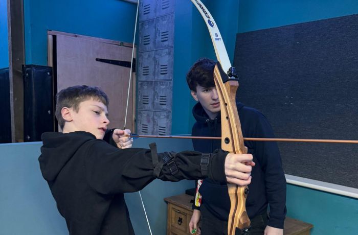 An instructor and young boy indoor archery