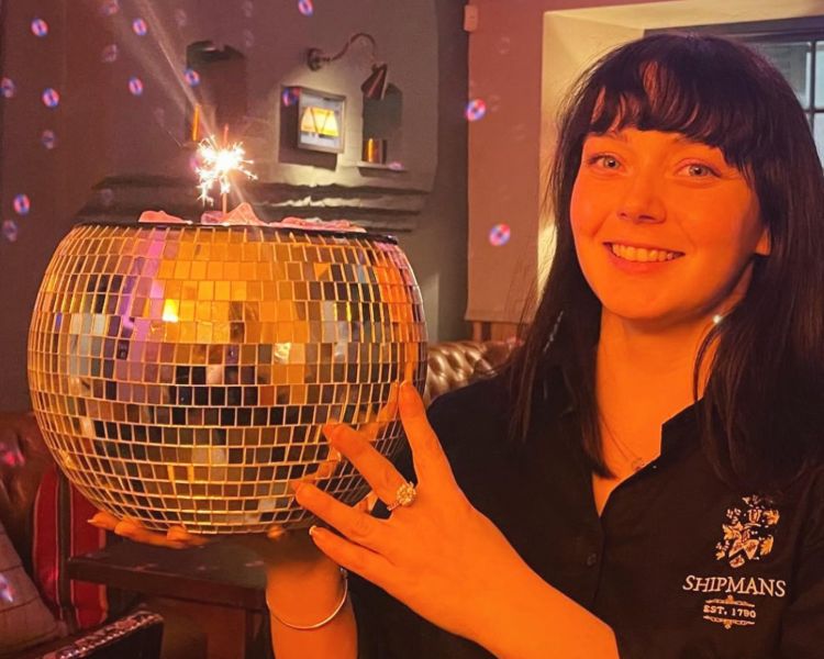 A staff member holding a disco ball cocktail