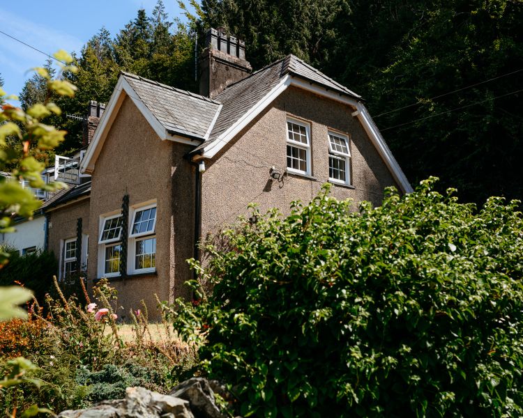 Side of cottage by woodland