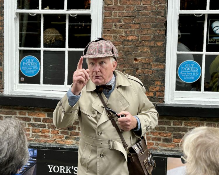 guide talking to group in front of building with blue plaques on a historical walking tour in york