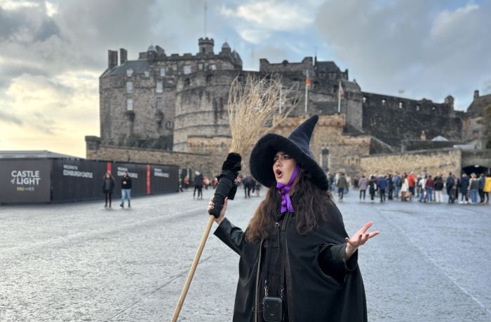 guide dressed as witch talking in front of edinburgh castle on a witches walking tour in edinburgh
