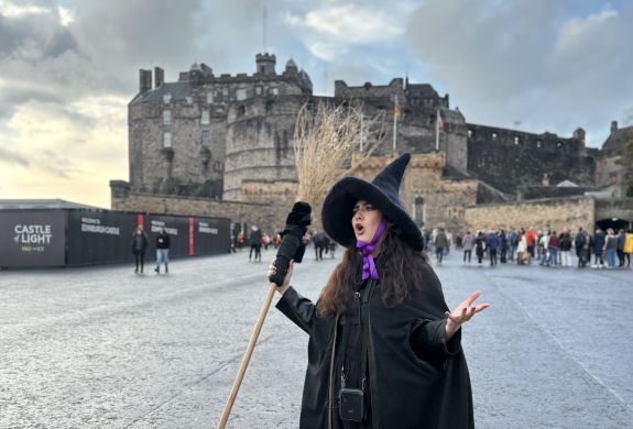 guide dressed as witch talking in front of edinburgh castle on a witches walking tour in edinburgh