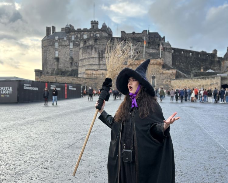 guide dressed as witch talking in front of edinburgh castle on a witches walking tour in edinburgh