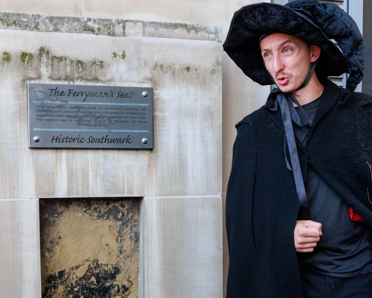 guide by wall plaque on a witches walking tour in london