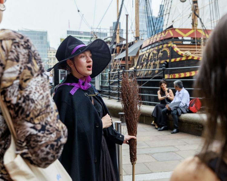 guide talking to group by boat on thames on a witches walking tour in london