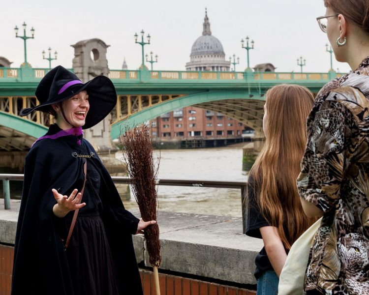 guide talking to group by river on a witches walking tour in london