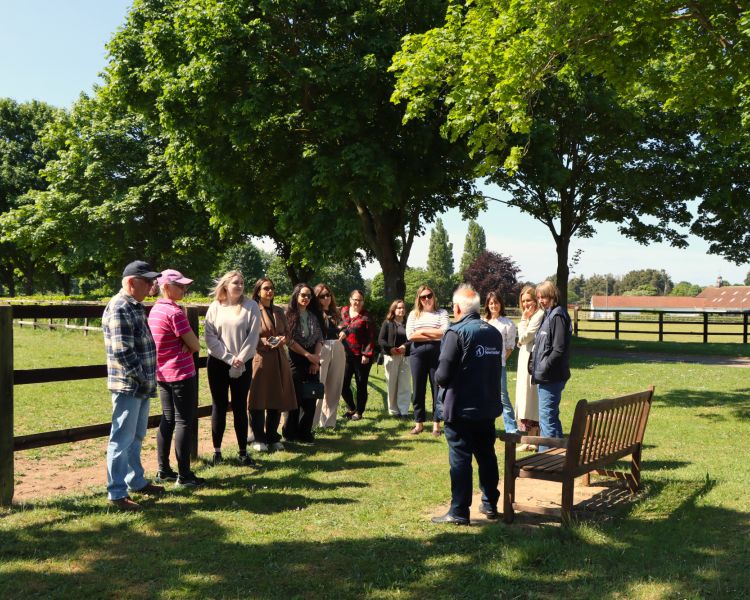 Tour group listening to guide next to paddock at newmarket
