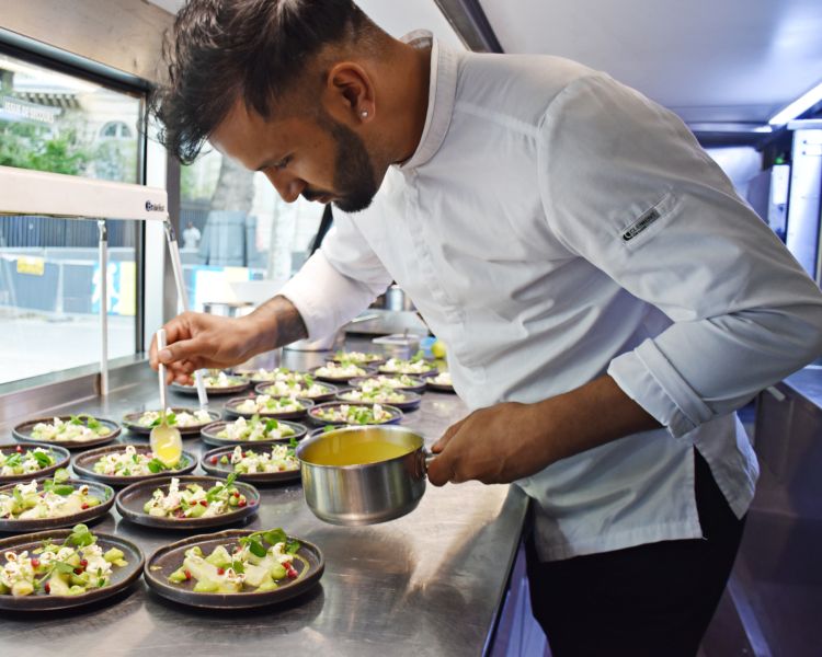 Chef plating up a meal on bustronome london dining experience