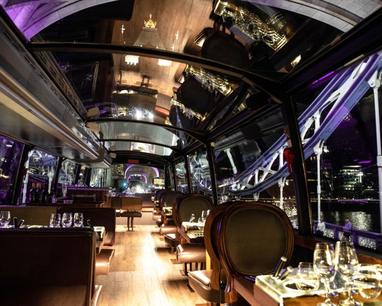 The top deck of the bustronome london dining bus lit up at night