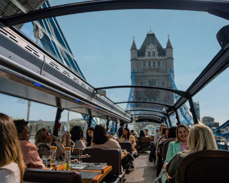 Top deck of bustronome london dining bus with diners and london views through windows