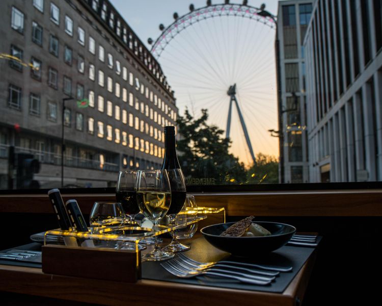 View of london eye through window of bustronome london dining bus at sunset