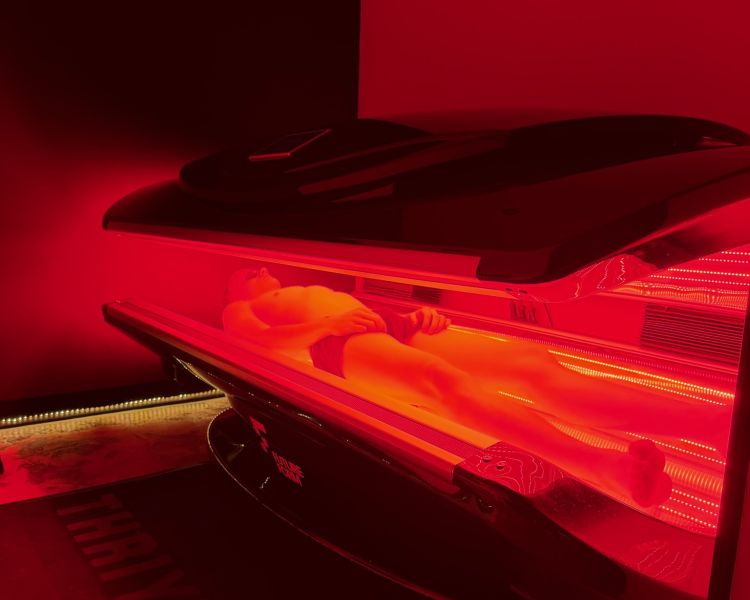 Person lying in red light therapy bed for treatment at thriyv in manchester