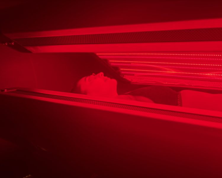 Woman lying on red light therapy bed at thriyv clinic