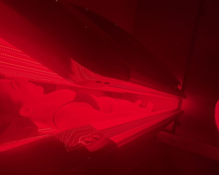 Woman lying on red light therapy bed for treatment at thriyv clinic