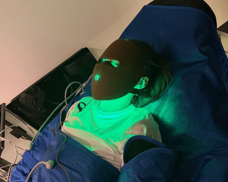Woman having lymphatic drainage treatment and wearing led face mask with green light
