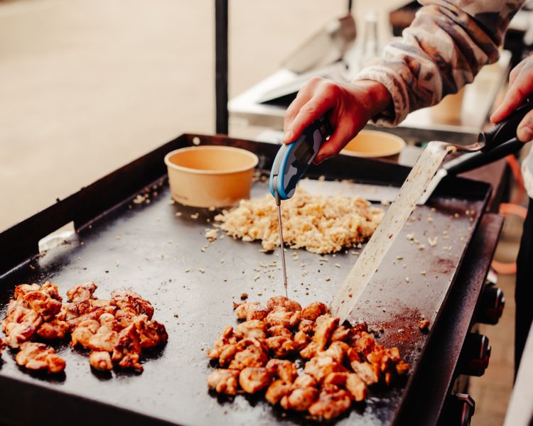 checking the temperature of meat cooking on a blackstone griddle bbq