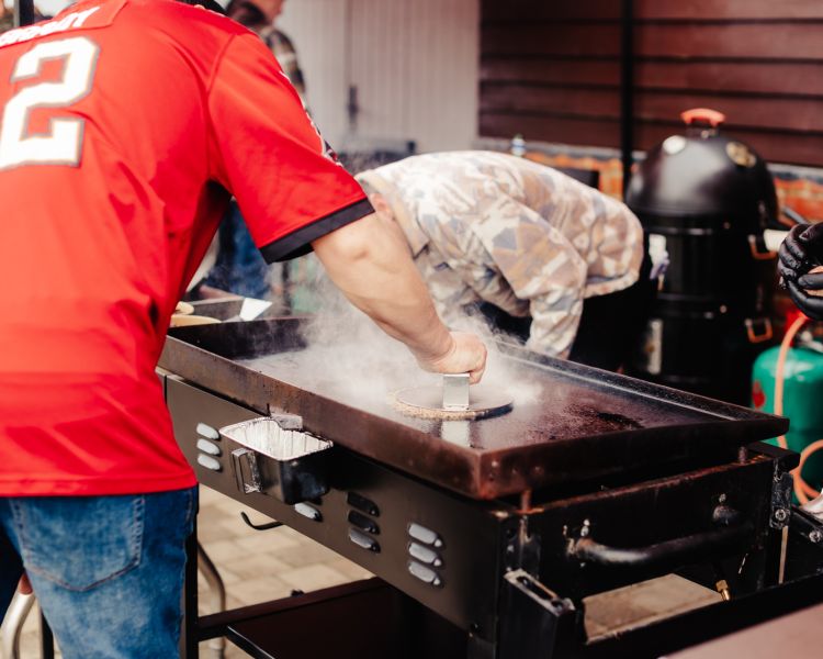 man cooking a smashed burger on a blackstone griddle bbq on a class learning how to use them