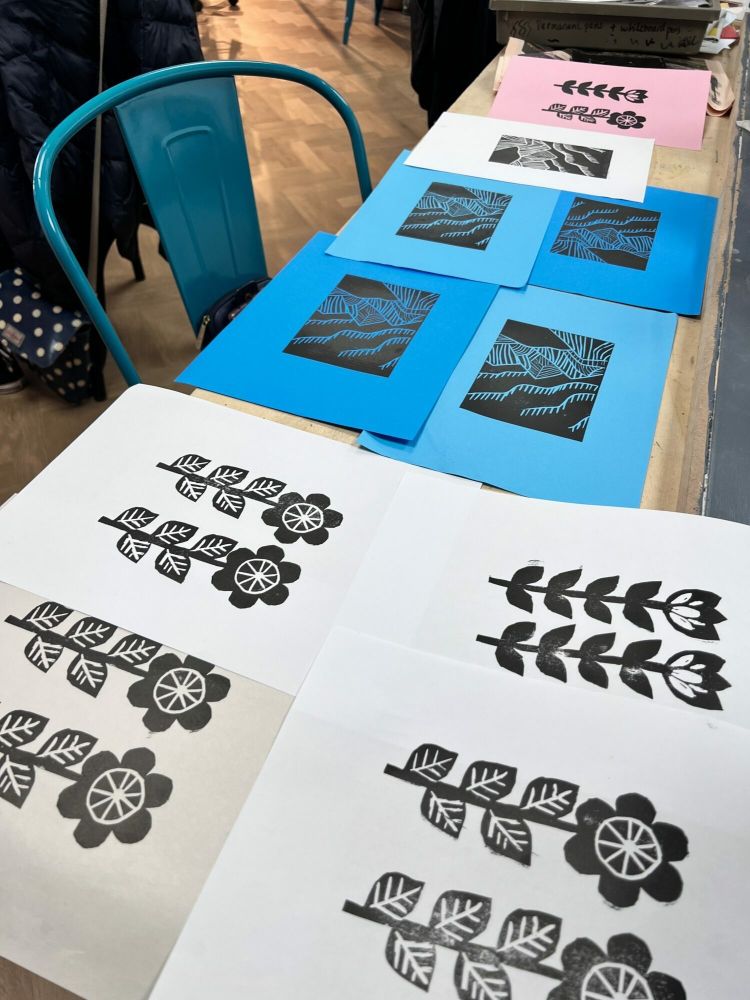 examples of printed designs drying on table made at a lino printing workshop