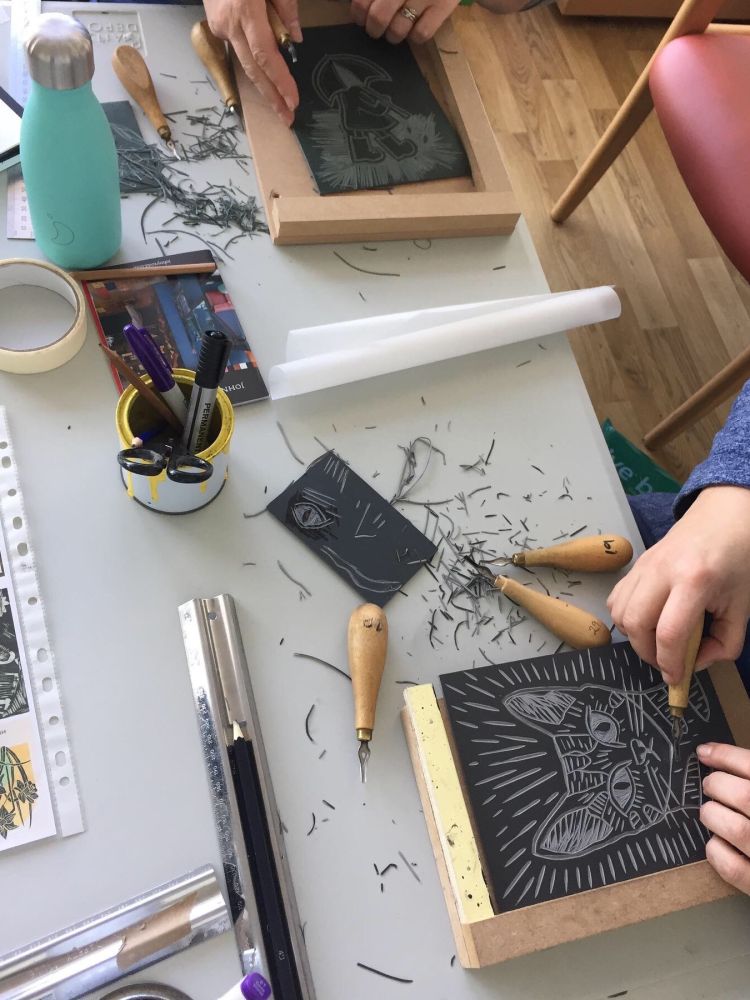 person cutting a cats face design into lino at a lino printing workshop