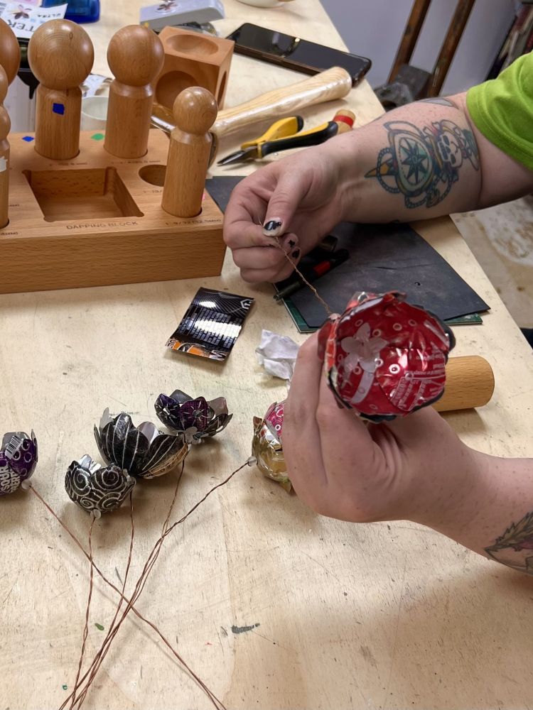 making a flower made from cut up recycled metal drinks cans