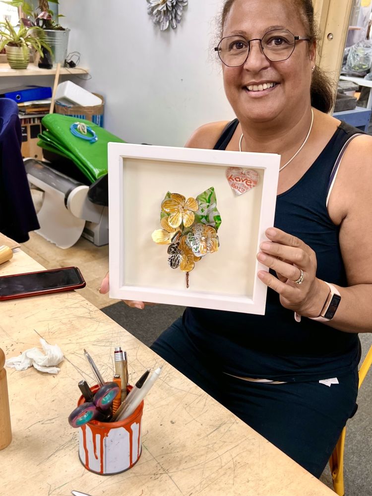 lady holding her framed flowers made from cut up recycled metal drinks cans