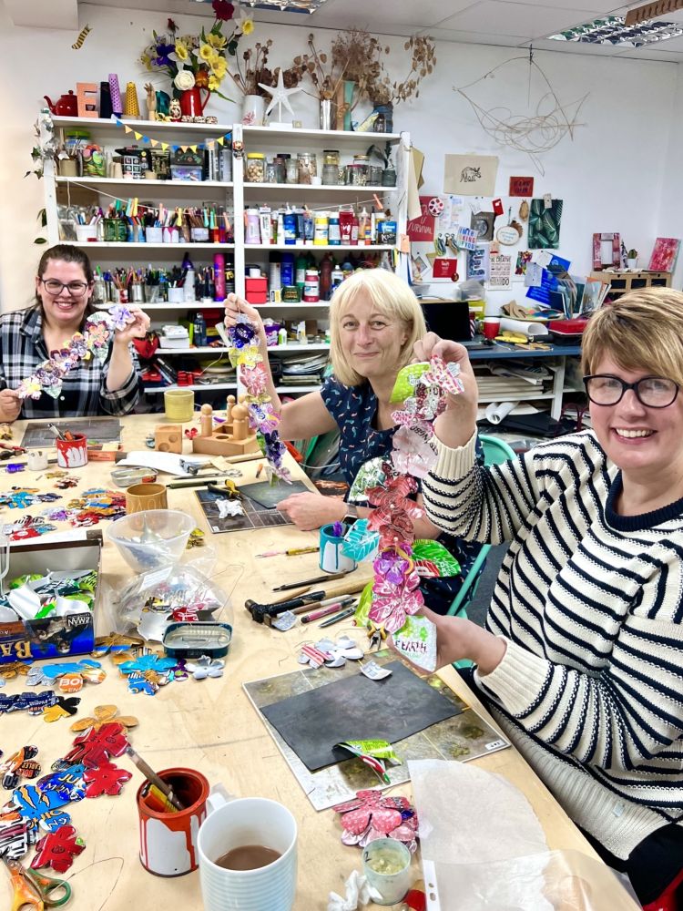 ladies at a craft workshop making flower garlands from recycled metal drinks cans