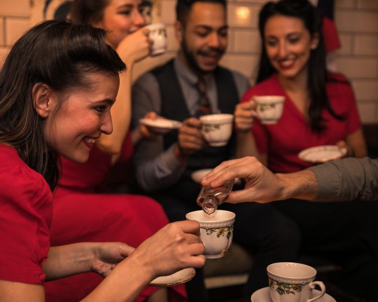 people drinking cocktails in teacups at cahoots underground 1940s style bar in london