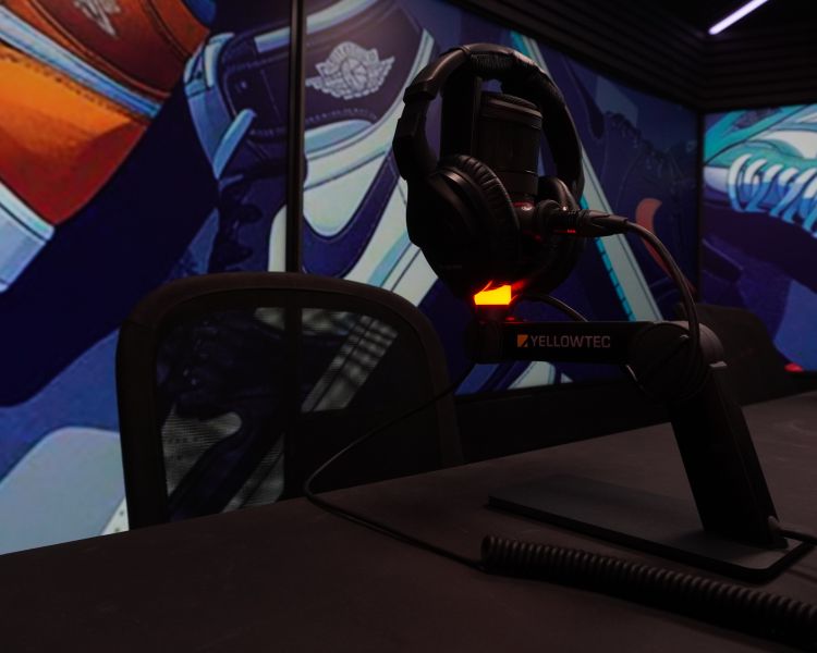 close up of a microphone on a desk in a podcast studio which has a tv wall