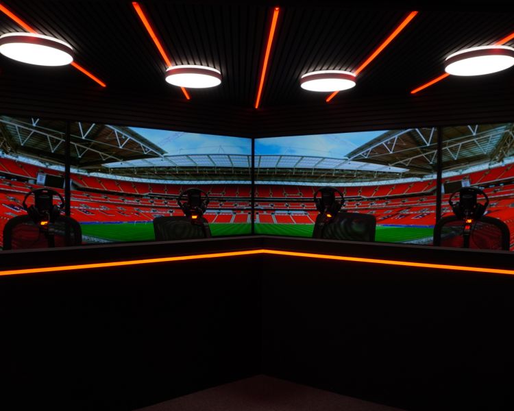 a podcast studio with football stadium on the tv wall behind the desks