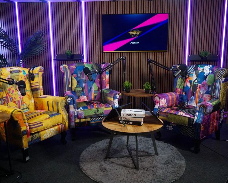 a podcast studio in exeter with coloured armchairs and microphones and tv on wall