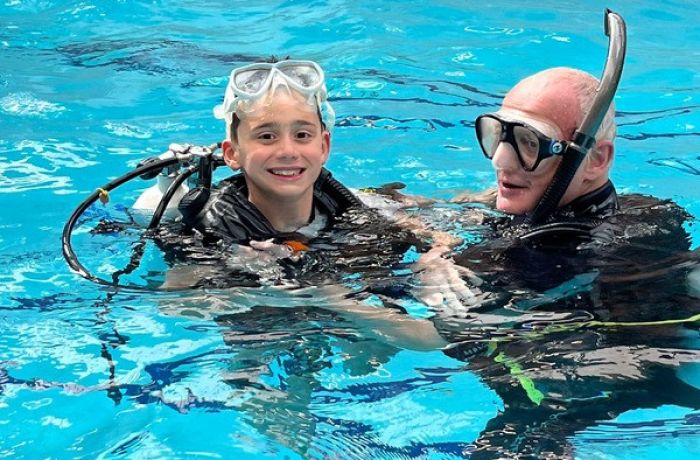 boy with instructor in indoor pool on scuba diving course