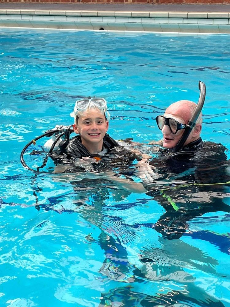 boy with instructor in indoor pool on scuba diving course