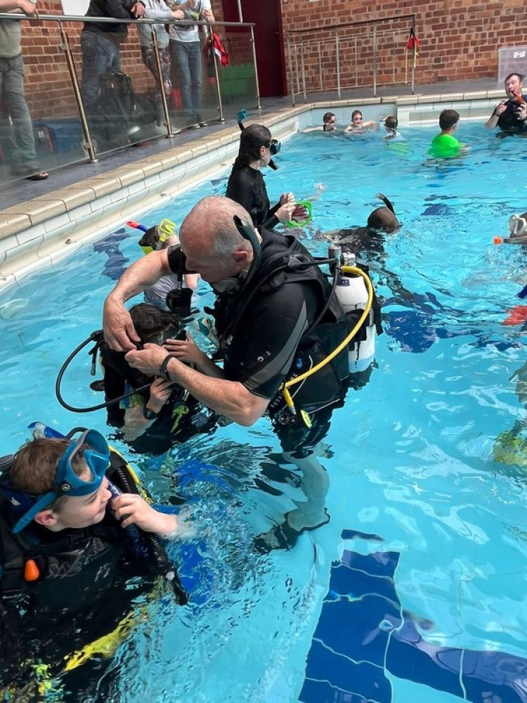 instructor with students in indoor pool on scuba diving course