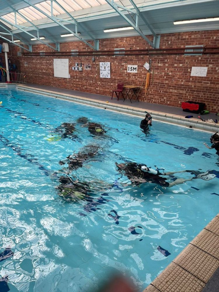 group under water in pool on scuba diving course