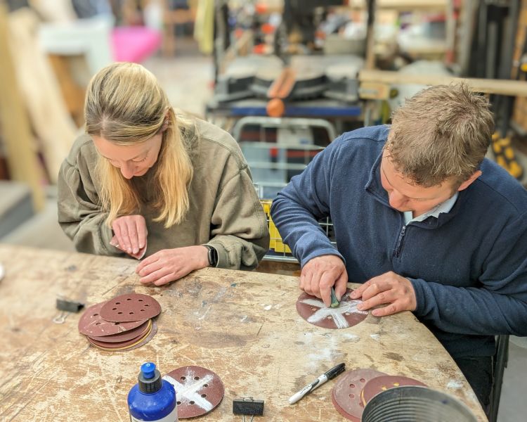 man and woman in workshop sanding resin art pieces