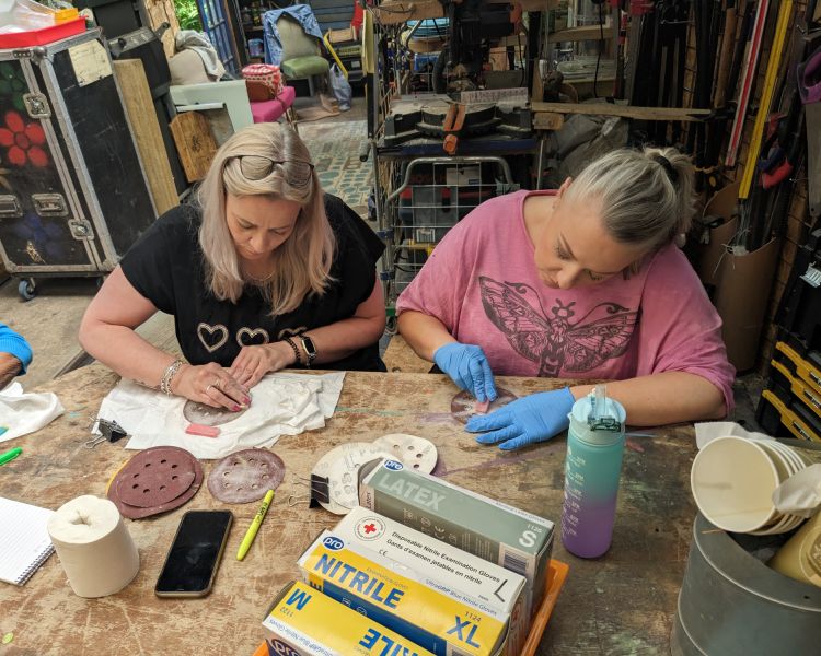 ladies sanding resin pieces made on a one day resin art course in somerset