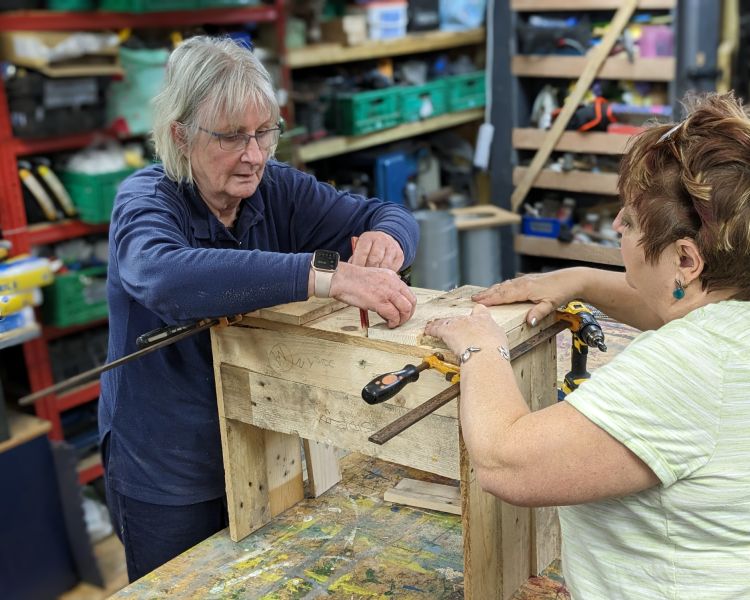 ladies working on a piece made from upcycled wooden pallets