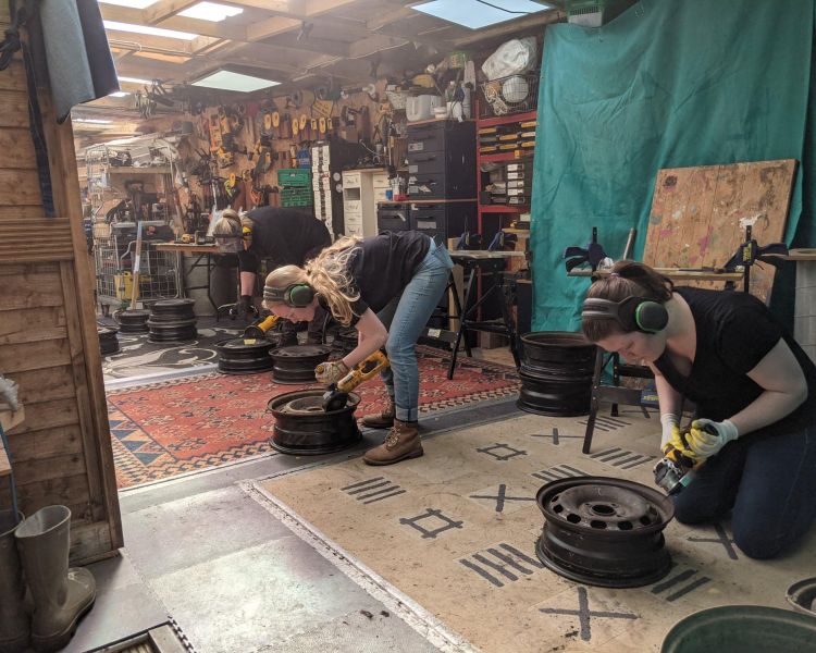 ladies in workshop cutting metal for fire pits