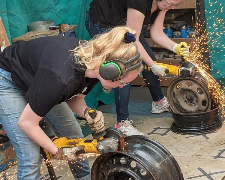 girl cutting metal to make a fire pit on one day course