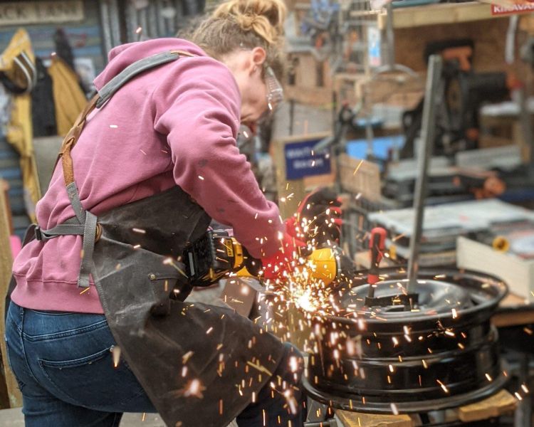 woman cutting metal to make a fire pit