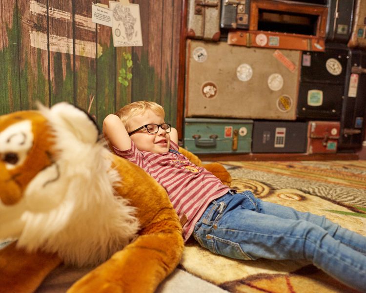 young boy lying on floor in zebra themed room at safari hotel at chessington world of adventures