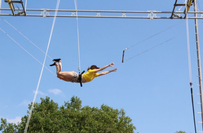 A lady mid air transferring on a trapeze