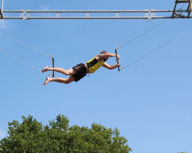 A man mid air transfer on a trapeze