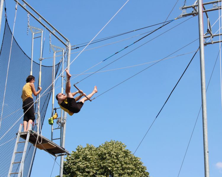 A man swinging on a trapeze sunny day