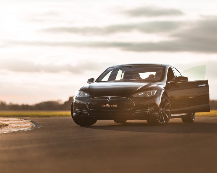 A black tesla model s p90d on track at sunset