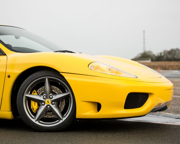 Side view of front wheel on yellow ferrari 360 moderna on track