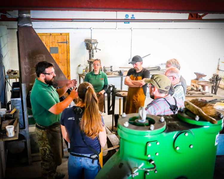 group listening to blacksmith instructor