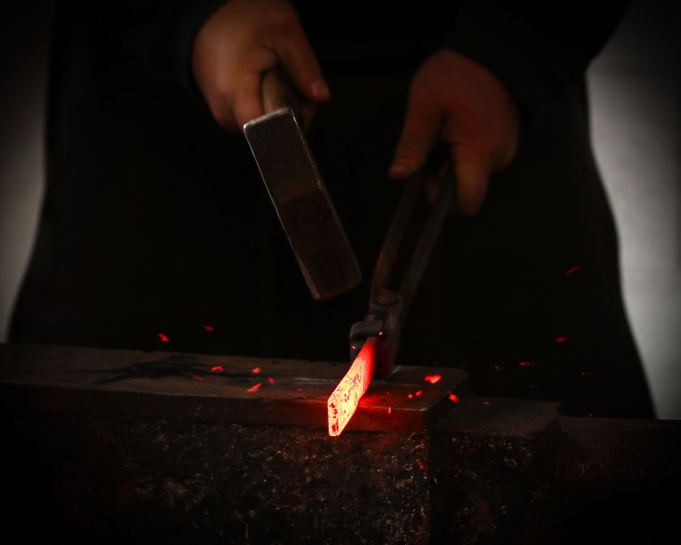 shaping hot metal with hammer on blacksmith experience in peak district