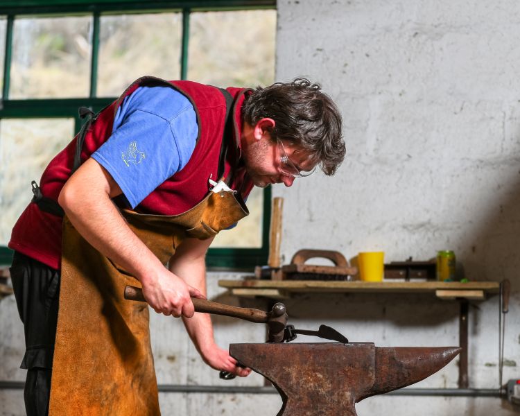 man shaping knife made on blacksmith experience in peak district