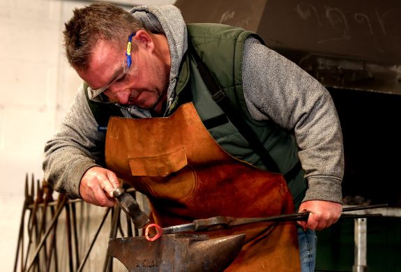 man shaping a bottle opener on a blacksmith day experience